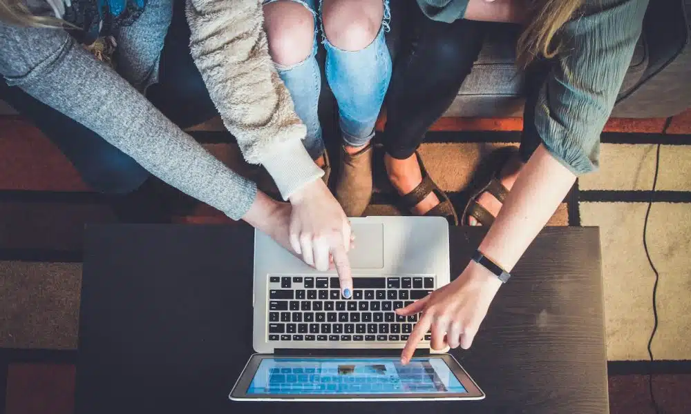 three person pointing the silver laptop computer