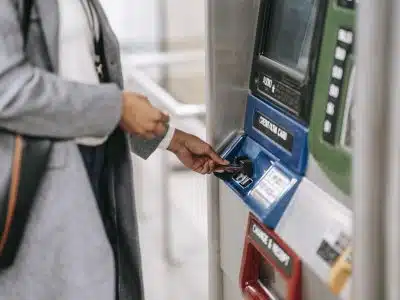 Side view of crop unrecognizable female in stylish clothes using credit card while buying metro ticket via electronic machine