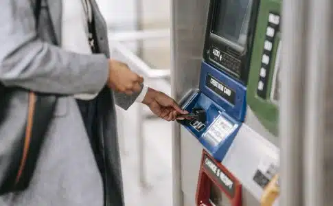 Side view of crop unrecognizable female in stylish clothes using credit card while buying metro ticket via electronic machine