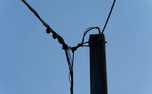 a telephone pole with wires and a blue sky in the background